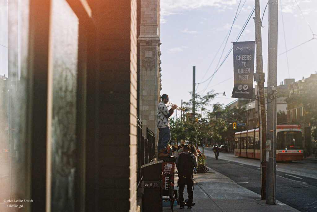 Man playing trumpet on top of a mailbox in Toronto.